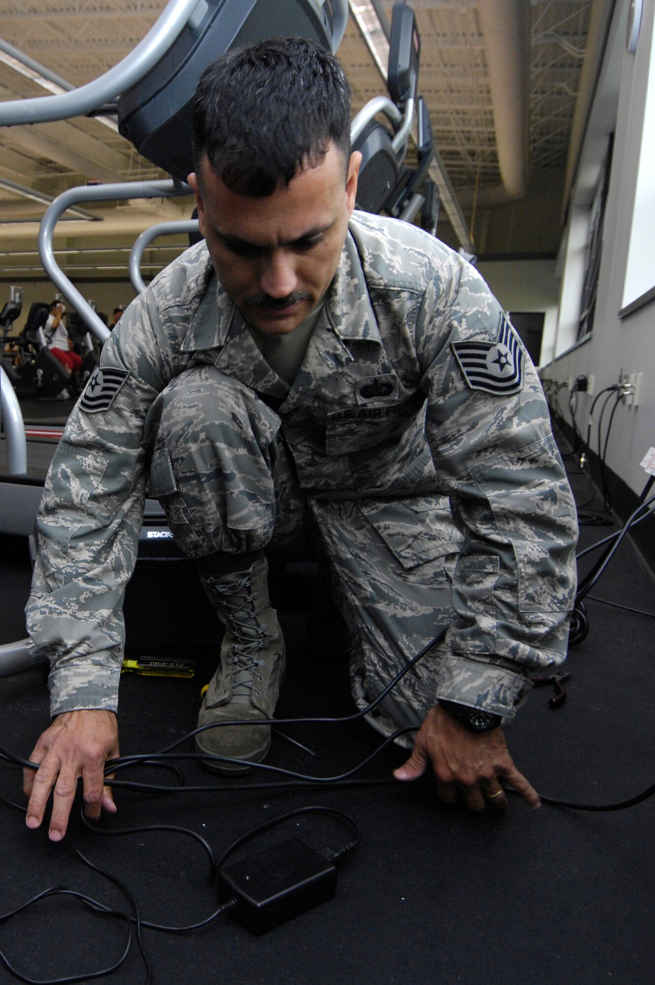 Tech. Sgt. Alexander Oritz aligns and organizes the wires from a treadmill at the Fitness and Sports Center on Joint Base Charleston, S.C., May 24, 2010. By organizing the wires, Sergeant Oritz helps eliminate tripping hazards and ensures that the gym is a safer place. Sergeant Oritz is a fitness specialist from the 482nd Force Support Squadron at Homestead Air Reserve Base, Fla. (U.S. Air Force Photo/Airman 1st Class Lauren Main)