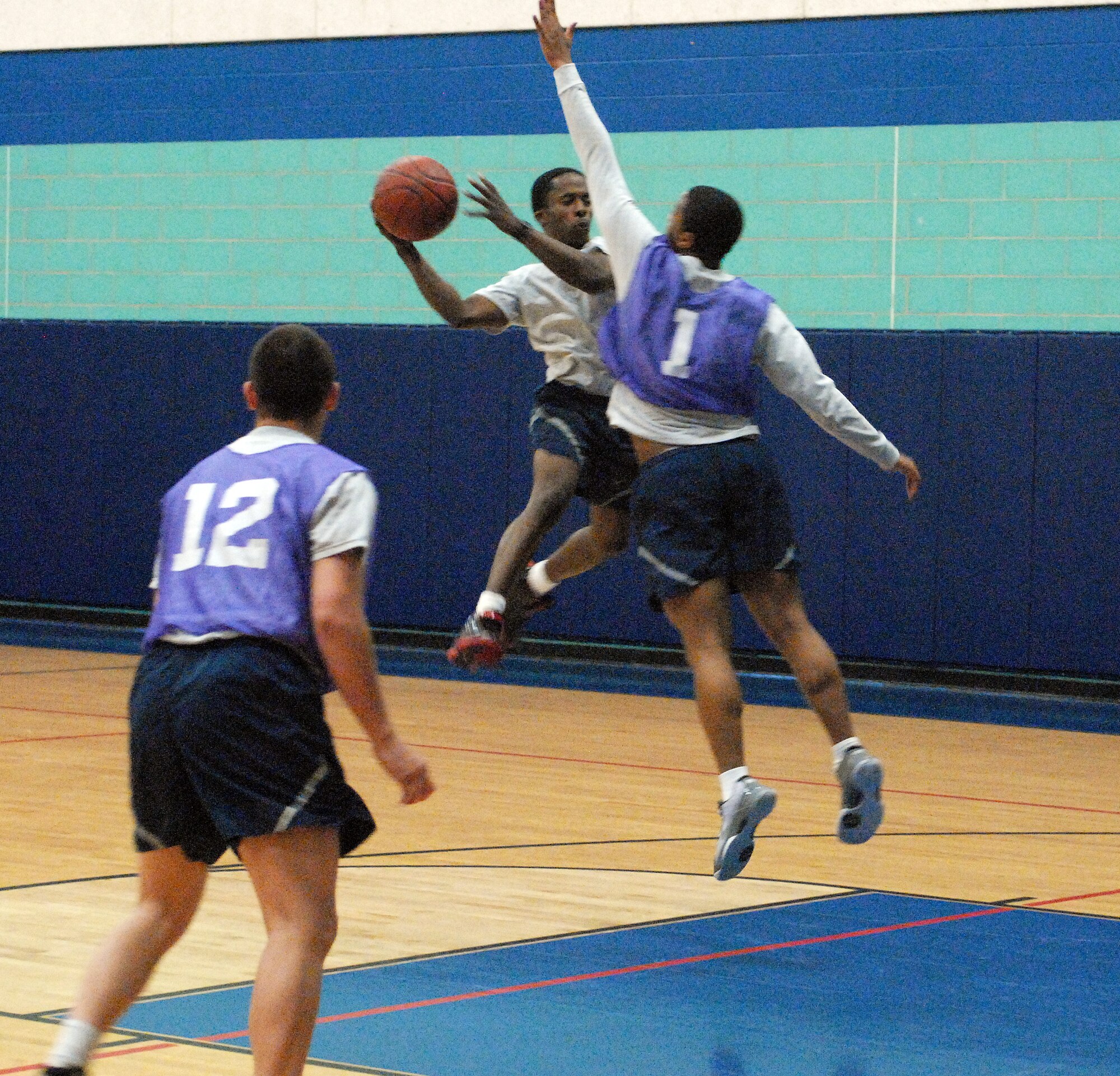Airman Basic Donovan Cross attempts to drive to the basket against members of the 17th Communication Squadron during the sports day 3 on 3 basketball tournament.  Sports day provided a variety of activities for all participants including volleyball, tennis, swimming and more. (U.S. Air Force photo/Master Sgt. Randy Mallard)