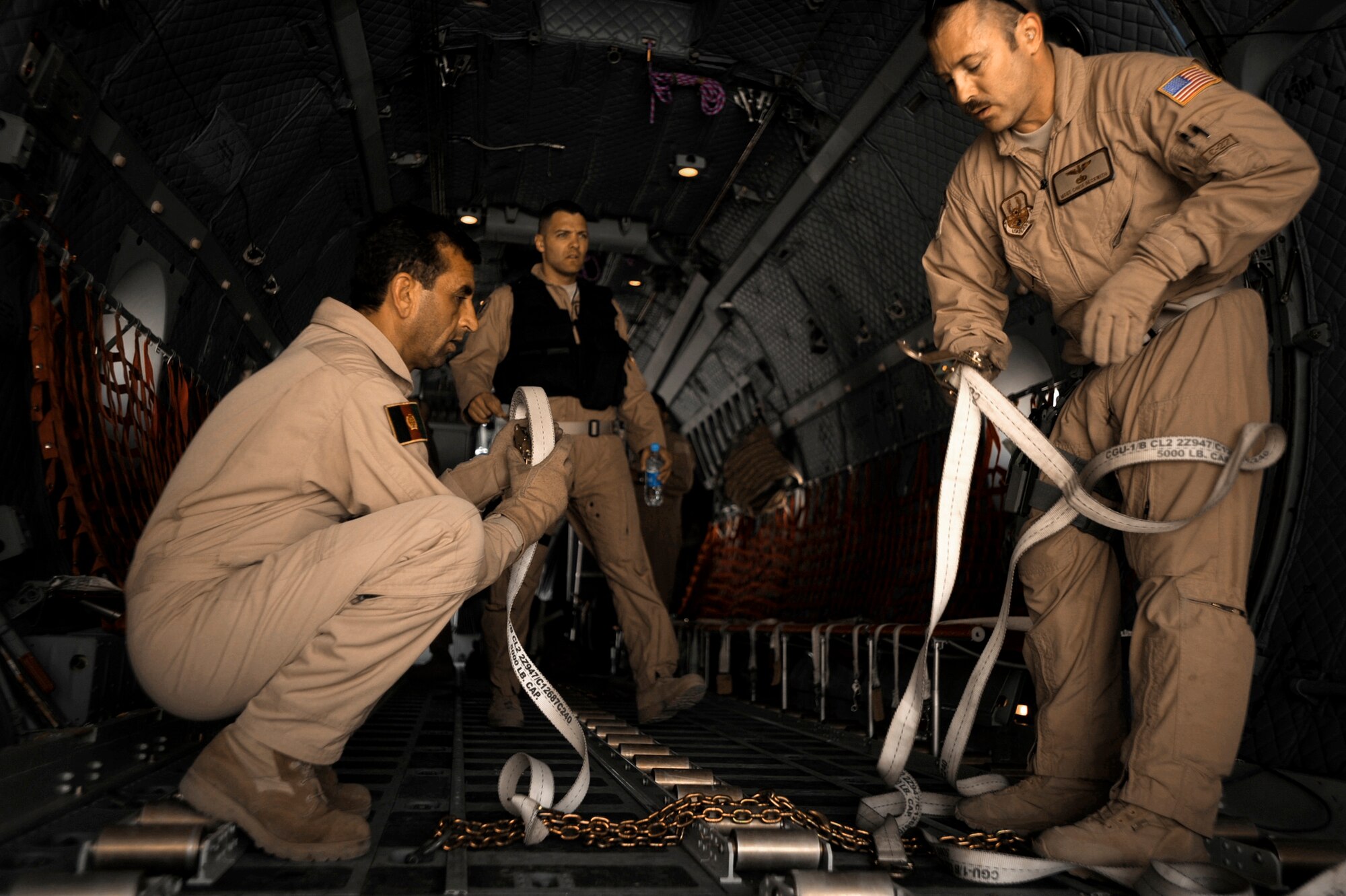 Afghan National Army Air Corps Sgt. Osman Sltamhmad and U.S. Air Force Master Sgt. Chris Beckwith put away loose cargo straps on a C-27 Spartan prior to the arrival of passengers May 15, 2010, at Kandahar Airfield, Afghanistan. Sergeant Sltamhmad is a C-27 loadmaster. Sergeant Beckwith is a C-27 loadmaster adviser assigned to the 538th Air Expeditionary Advisory Squadron. (U.S. Air Force photo/Staff Sgt. Manuel J. Martinez)
