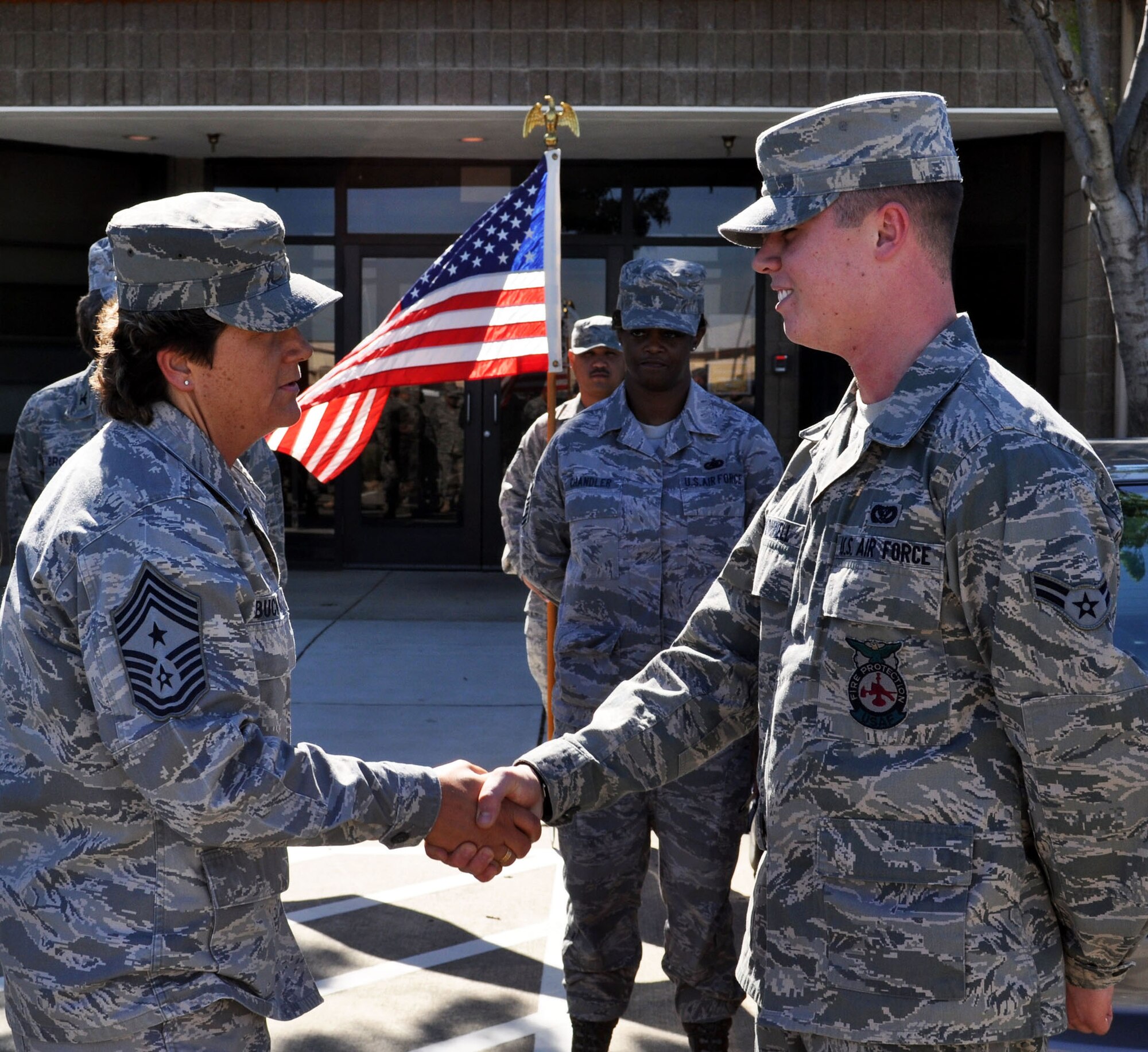 TRAVIS AIR FORCE BASE, Calif. -- Chief Master Sgt. Kathleen Buckner, 349th Air Mobility Wing command chief, "coins" Amn. William Wonnell in recognition of the triple honors received from Air Force BMT and the Louis F. Garland Fire Academy, Sheppard AFB, Texas. Amn. Wonnell is the newest fire fighter assigned to the 349th Civil Engineer Squadron. (U.S. Air Force photo/Senior Master Sgt. Ellen L. Hatfield)