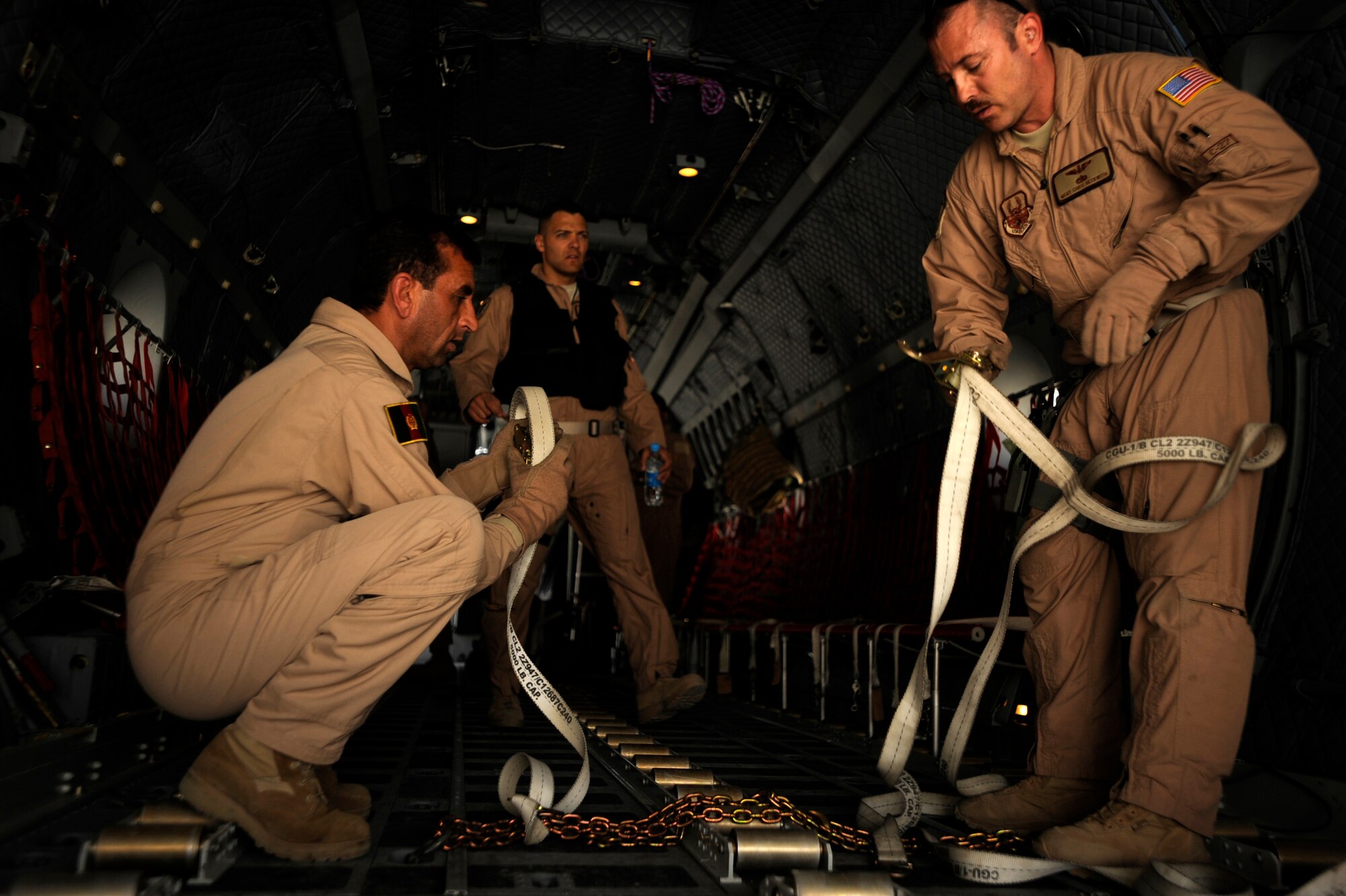 Afghan National Army Air Corps Sgt. Osman Sltamhmad, a C-27J Spartan loadmaster, and U.S. Air Force Master Sgt. Chris Beckwith, a C-27J Spartan loadmaster advisor assigned to the 538th Air Expeditionary Advisory Squadron, put away loose cargo straps on a C-27J aircraft prior to the arrival of passengers May 15, 2010, at Kandahar Airfield, Afghanistan.   (U.S. Air Force/ Staff Sgt. Manuel J. Martinez/released)  
