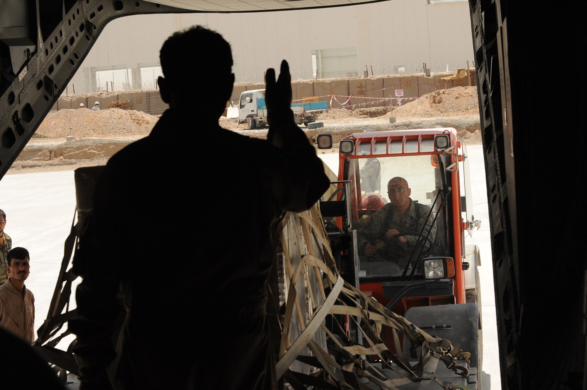 Afghan National Army Air Corps Sgt. Osman Sltamhmad, C-27J loadmaster, guides U.S. Air Force Master Sgt. Brian Aiken, an aerial porter advisor assigned to the 443rd Air Expeditionary Advisor Squadron, who uses a forklift to unload cargo from a C-27J Spartan, May 15, 2010, at Kandahar Airfield, Afghanistan.  (U.S. Air Force/ Staff Sgt. Manuel J. Martinez/released)  