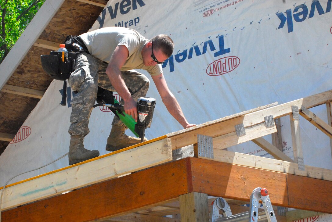 A U.S. Army soldier uses a nail gun to secure the roofing board over a porch during this 
year's annual training building three cabins at the Disabled Veterans Rest Camp in Marine St. Croix, Minn., May 19, 2010.