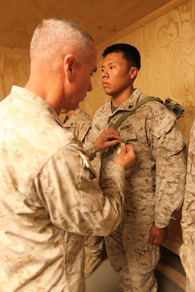 (Left) Brig. Gen. Charles L. Hudson, 51, from Zirconia, North Carolina, commanding general of 1st Marine Logistics Group (Forward), presents the Navy and Marine Corps Achievement Medal to Cpl. Nalton B. Antonio, 22, from Albuquerque, N.M., heavy equipment operator with 7th Engineer Support Battalion, 1st MLG (FWD), May 25. Five Marines from 7th ESB were awarded Navy and Marine Corps Achievement Medals for their ‘heroic actions’ in helping contain a fire at the Supply Management Unit lot on Camp Leatherneck, Afghanistan, May 16. The cause of the fire is under investigation.