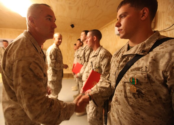 (Left) Brig. Gen. Charles L. Hudson, 51, from Zirconia, North Carolina, commanding general of 1st Marine Logistics Group (Forward), congratulates Lance Cpl. Ryan M. Williams, from Water Bury, Conn., heavy equipment operator with 7th Engineer Support Battalion, 1st MLG (FWD), after presenting the Marines with Navy and Marine Corps Achievement Medals, May 25. Five Marines from 7th ESB were awarded Names for their ‘heroic actions’ in helping contain a fire at the Supply Management Unit lot on Camp Leatherneck, Afghanistan, May 16. The cause of the fire is under investigation.