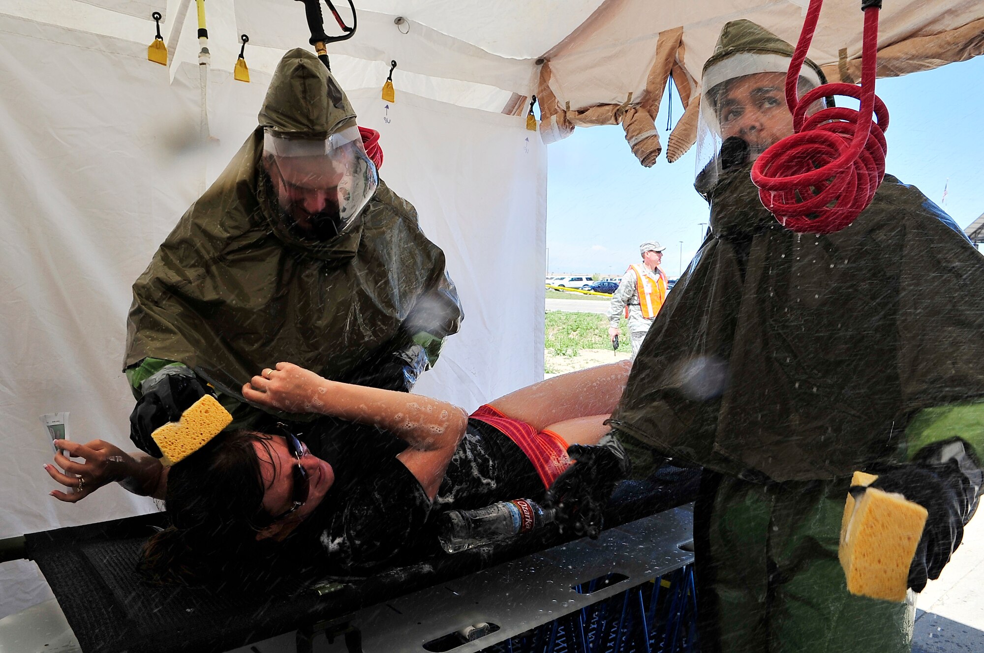 BUCKLEY AIR FORCE BASE, Colo. --  Staff Sgts. Zachariah Coyner, left, and Jesus Almero, both of the 460th Medical Operations Squadron, scrub down Anna Welby, 460th Space Wing Safety Office, during an All-Hazards Response Training exercise May 21. 460th Medical Group emergency response teams set up a hazardous-material decontamination line after a scenario input involving the release of a chemical agent. (U.S. Air Force photo by Staff Sgt. Kathrine McDowell)