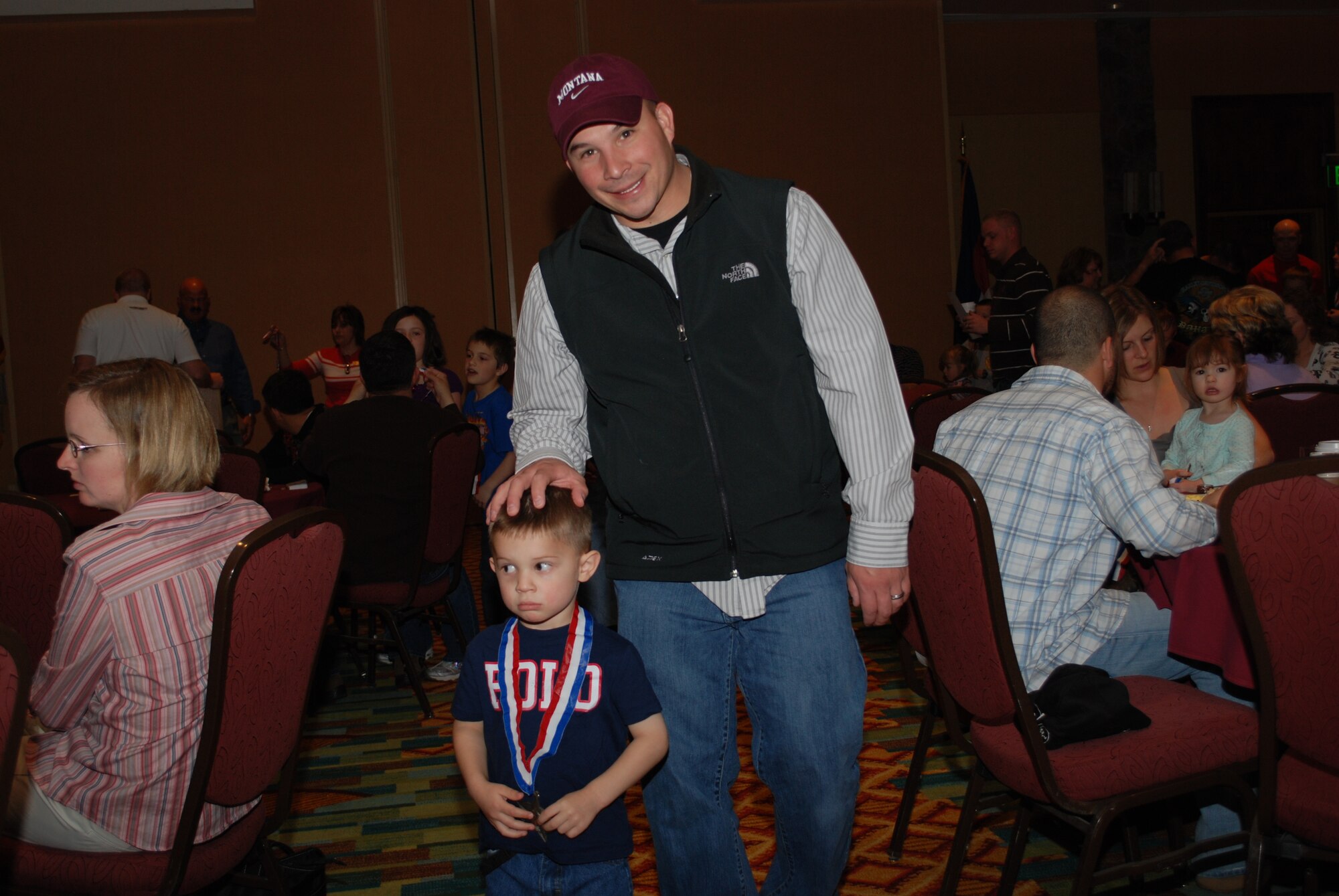 Air Force Reservist Tech. Sgt. Jody Sanchez, 302nd Security Forces Squadron unit deployment manager, walks back to his seat with his son, Thomas after presenting Thomas with a medal inscribed with the words “We Serve Too” during a April 24 Colorado National Guard Yellow Ribbon Reintegration Program post-deployment event in Vail, Colo. YRRP was established in 2007 to assist Guard and Reserve members as they return to their daily lives after being deployed to a combat zone. Members and families who have or will deploy are welcome and encouraged to participate in future YRRP events. The 302nd AW's Airman and Family Readiness Center can provide additional information on future programs. (U.S. Air Force photo/Capt. Jody Ritchie)