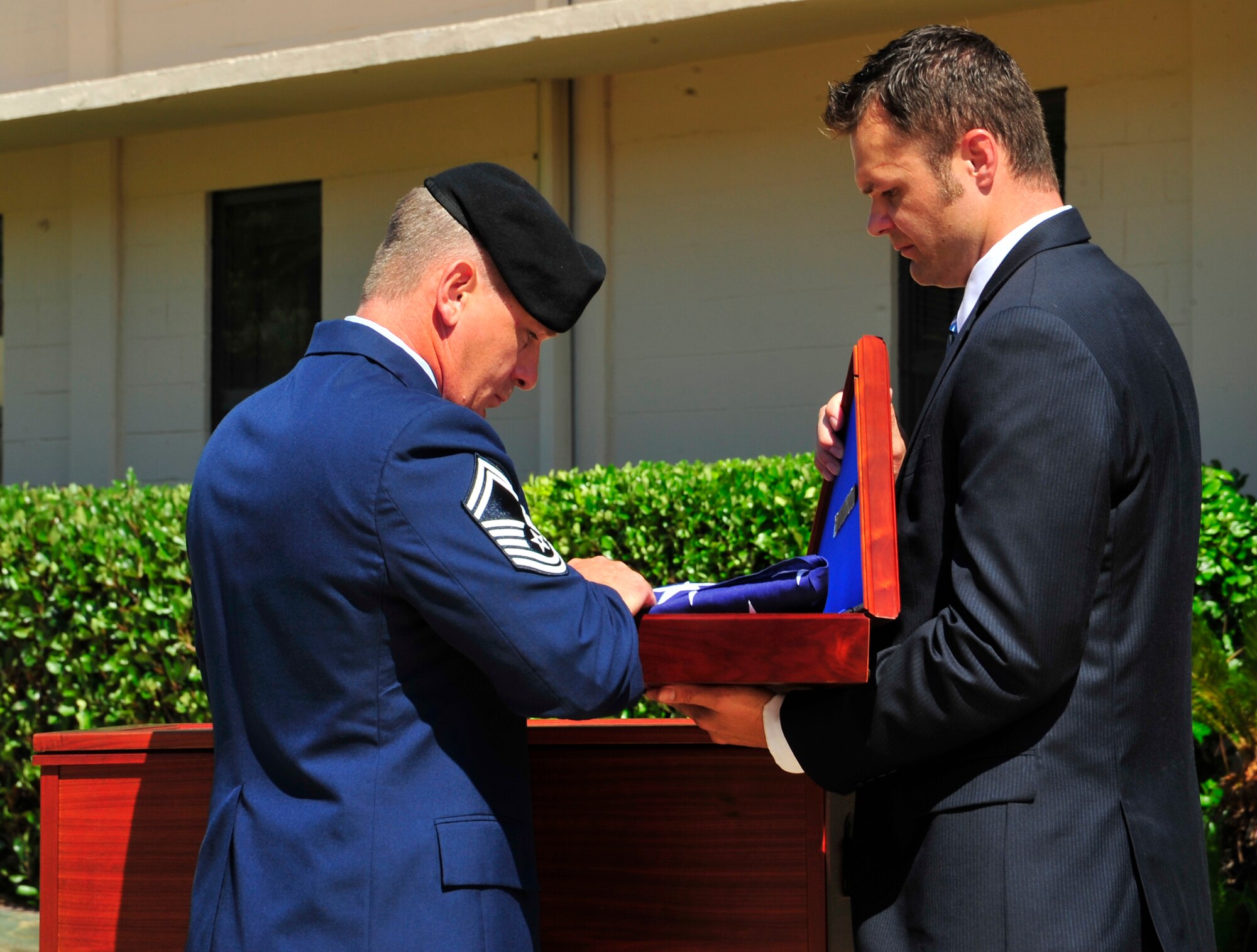 Left, Senior Master Sgt. Troy Lundquist, Tactical Air Control Party Schoolhouse superintendent, and Charlie Keebaugh, former TACP and president of the TACP association, place an American Flag inside a display case that was presented to the Smith family during a memorial ceremony May 26, 2010. While deployed in support of Operation Enduring Freedom, Airman Smith, a TACP assigned to the 10th Air Support Operations Squadron, was killed along with three other U.S. servicemembers when his unit encountered multiple improvised explosive devices Jan. 3, 2010. (DoD photo by U.S. Air Force Senior Airman Sheila Devera)