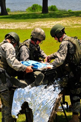 From left to right, U.S. Air Force MSgt. Kenneth Bailey, Surgical technician, Lt. Col. Jon Winker, General Surgeon, and Maj. Sean O'Brien, Orthopedic Surgeon, all assigned to the 1st Special Operations Support Squadron, perfom a simulated life saving operation during a ground rescue opepation demonstration at Hurlburt Field, Fla., May 20, 2010. Members of the Care Coaltions saw first hand how Air FOrce SPecial Operations Command Airmen work together to successfully complete the mission. The Care Coalition is an advocacy organization that works to enhance the quality of life of wounded USSOCOM service members and their families. (DoD photo by Senior Airman Sheila deVera)