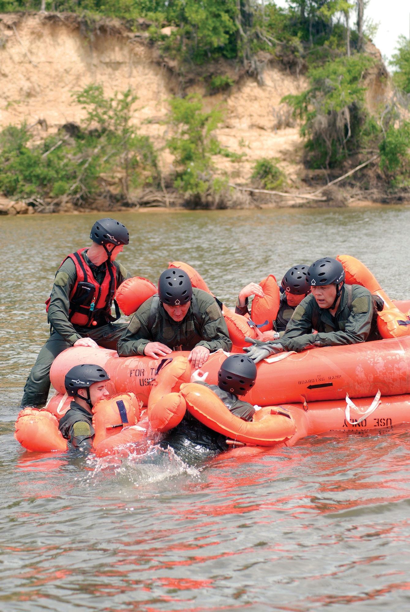Senior Airman Chad Braunschweig (red floatation vest) observes as members of the operations group help each other into a 20-man raft during the 908th Airlift Wing's water-survival training at the Alabama River.  (Air Force photo by Gene H. Hughes)