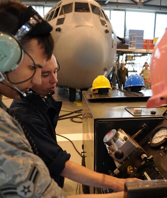 U.S. Air Force Airman 1st Class Randy Bennett and Timothy Nevins, 86th Maintenance Squadron isochronal crew chiefs, adjust the pressure on a compressor to do a full aircraft jacking during an isochronal inspection, Ramstein Air Base, Germany, May 26, 2010. This is the first C-130J all active duty isochronal inspection done in the Air Force. (U.S. Air Force Photo by Airman 1st Class Caleb Pierce)