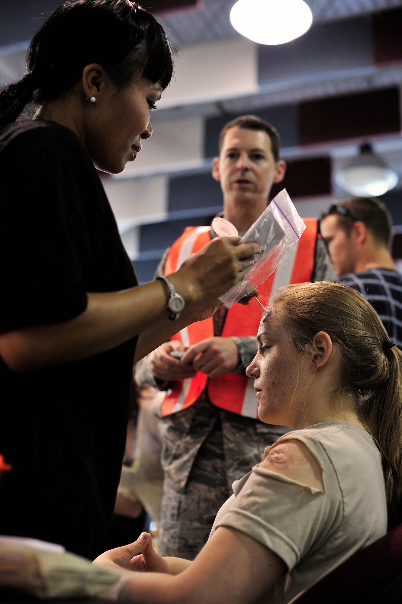 BUCKLEY AIR FORCE BASE, Colo. -- Tech. Sgt. Teresa Forward, 460th Medical Operations Squadron, applies moulage to Airman 1st Class Brittany Carlisle, 460th Comptroller Squadron, before an All-Hazards Response Training exercise May 21. These mock injuries provide emergency responders more realistic training to assess the care of crisis victims. (U.S. Air Force photo by Staff Sgt. Kathrine McDowell)