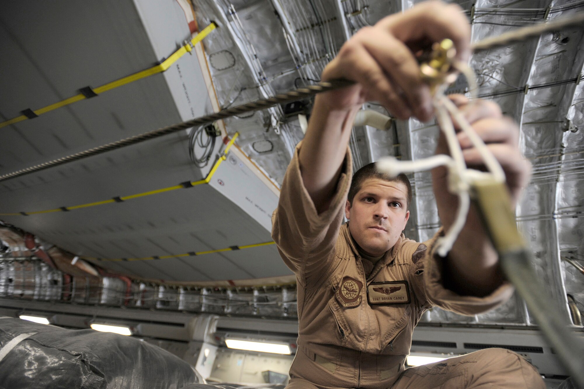 Staff Sgt. Bryan Carey hooks parachute draw cords to container-delivery-system bundles prior to take off for an airdrop mission May 9, 2010, at an undisclosed air base in Southwest Asia. Sergeant Carey is a C-17 Globemaster III loadmaster assigned to the 816th Expeditionary Airlift Squadron. (U.S. Air Force photo/Staff Sgt. Manuel J. Martinez)
