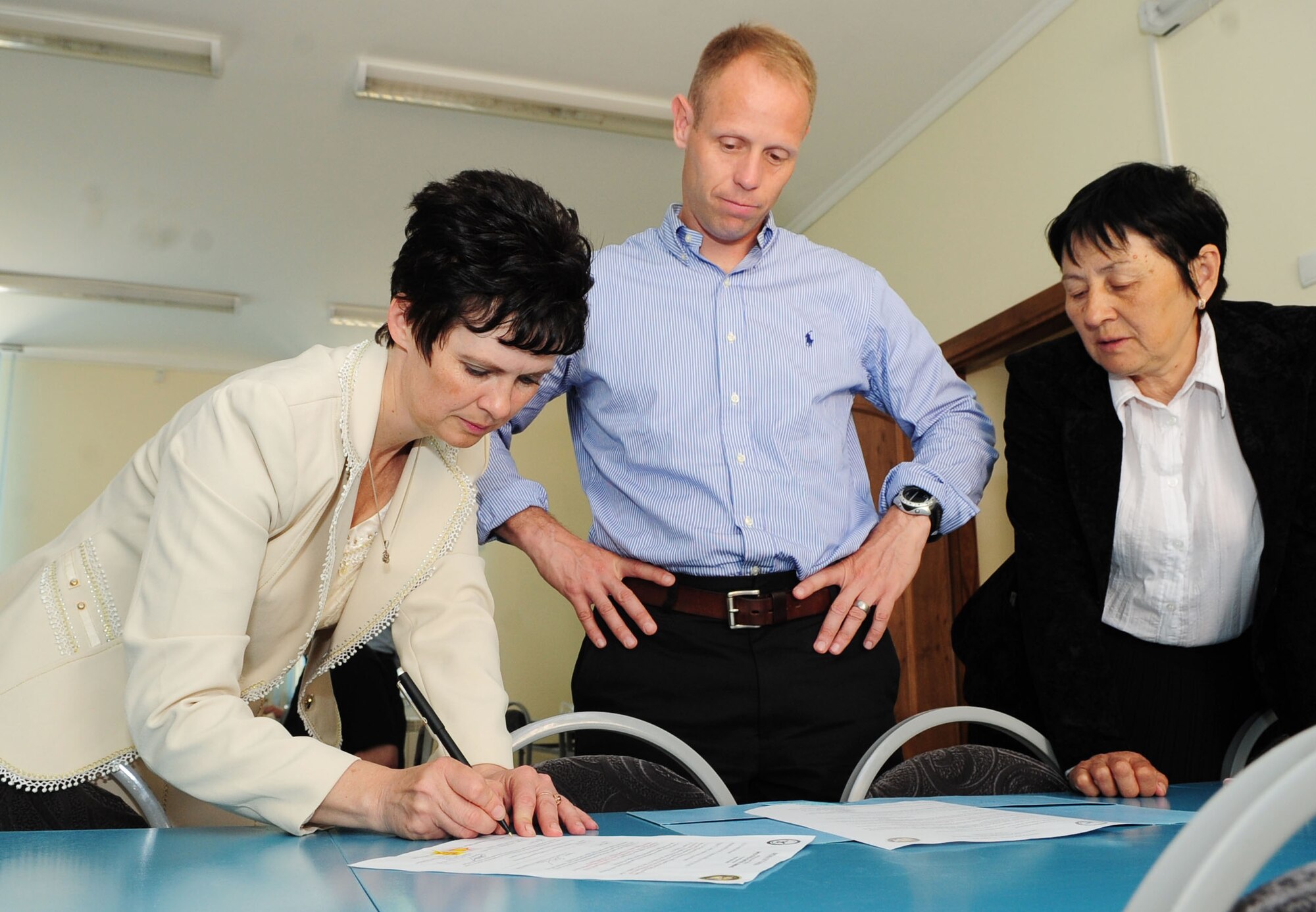 Olga Voroshikhina, Birdik Village School Principal, signs registration papers for a bus donated by the Transit Center at Manas, Kyrgyzstan, during a graduation ceremony for the school May 25, 2010. Colonel Holt presented the school with the bus during his speech. (U.S. Air Force photo/ Senior Airman Nichelle Anderson/ released)