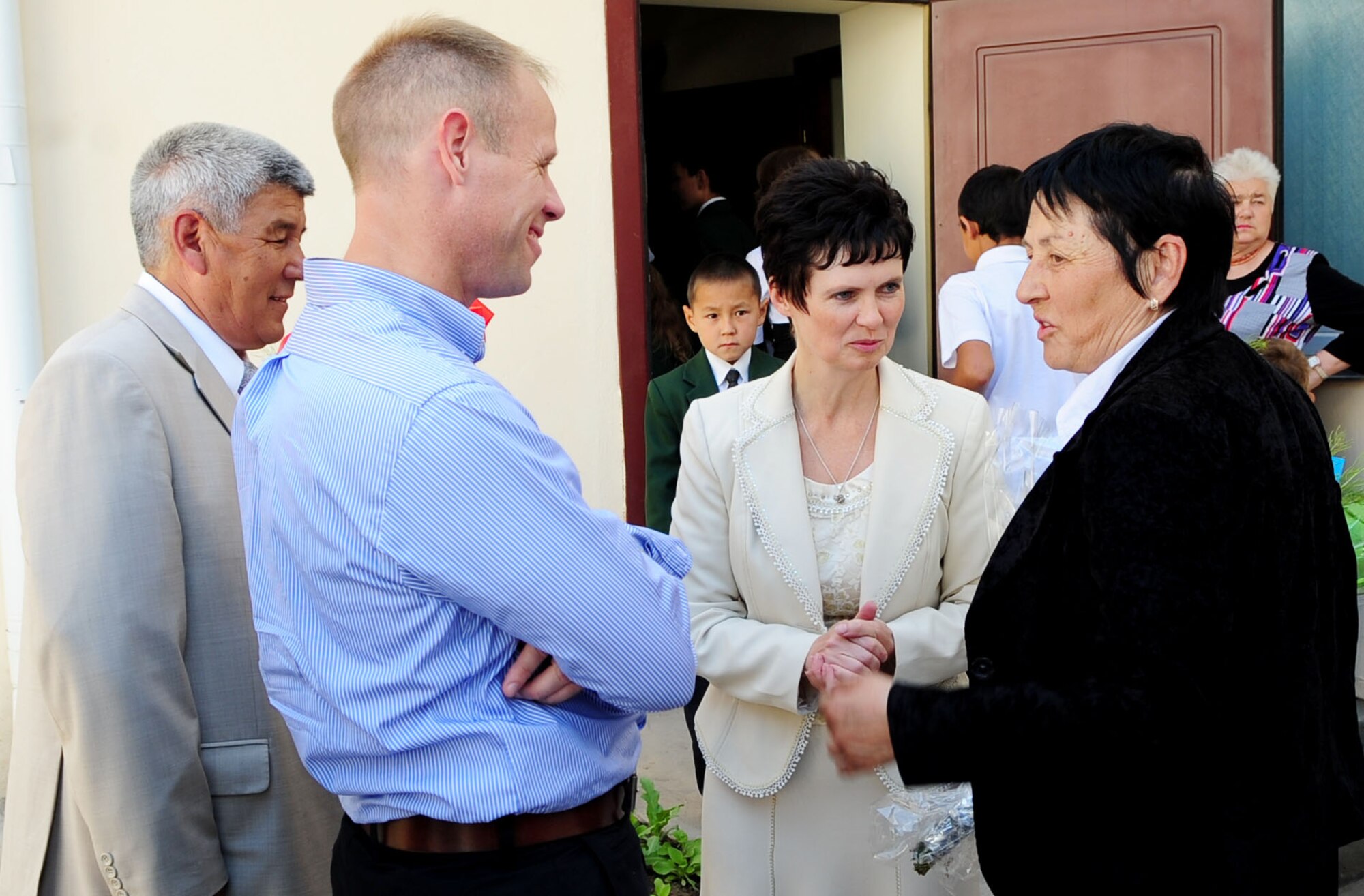 Ms. Valentina Turabekova, Special Assistant to the commander, speaks with Col. Blaine Holt, Transit Center Director; Director of Imarat Story Construction Project Mr. Beishembek Imanaliev; and Olga Voroshikhina, the Birdik Village School Principal, after the graduation ceremony for children of the Birdik Village School, May 25, 2010. Airmen from the Transit Center were invited to the graduation ceremony to help celebrate the end of the first school year since the completion of a recent reconstruction project. The project, which cost about $540,000, was funded by the Air Force and volunteer efforts from Airmen at the Transit Center at Manas. They celebrated the ribbon cutting Sept. 1, 2009. (U.S. Air Force photo/ Senior Airman Nichelle Anderson/ released)