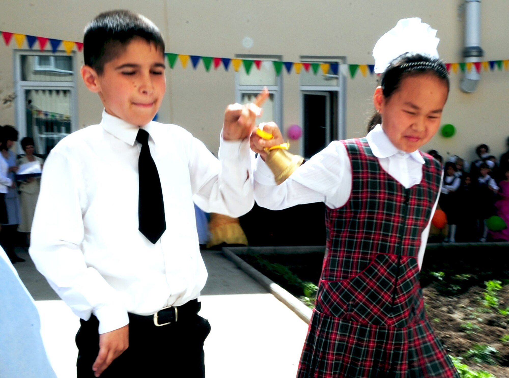 Children from the Birdik Village School, Kyrgyzstan, ring the final bell culminating the end of the school year during a graduation ceremony at the school May 25, 2010. Airmen from the Transit Center were invited to the graduation ceremony to help the children celebrate the end of the first school year since the completion of the reconstruction project. The project, which cost about $540,000, was funded by the Air Force and volunteer efforts from Airmen at the Transit Center.  The ribbon cutting was held Sept. 1, 2009. (U.S. Air Force photo/ Senior Airman Nichelle Anderson/ released)