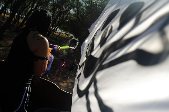 JOINT BASE PEARL HARBOR HICKAM, Hawaii -- Senior Airman Yommala Xaysanith, 15th Aircraft Maintenance Squadron, fires upon parade watchers during the annual Beach Bum Parade May 21 on Hickam. The pirate ship themed float utilized water balloons, water guns and water cannons to douse spectators as they rolled along the three-quarter mile and water hoses as they rolled by in the parade. The parade began at Bishop's Point Pier and ended at Hickam Harbor with free food and entertainment at Foster Point Pavilion. Those who wanted to were able to campout at Hickam Harbor after the parade for a fun, family night, gathered around a campfire for free s'mores. Once the sun set, campers enjoyed a movie on the beach on a large outdoor movie screen. The 15th Maintenance Group took first prize for the second year in a row for the best float. (U.S. Air Force photo/Staff Sgt. Mike Meares)
