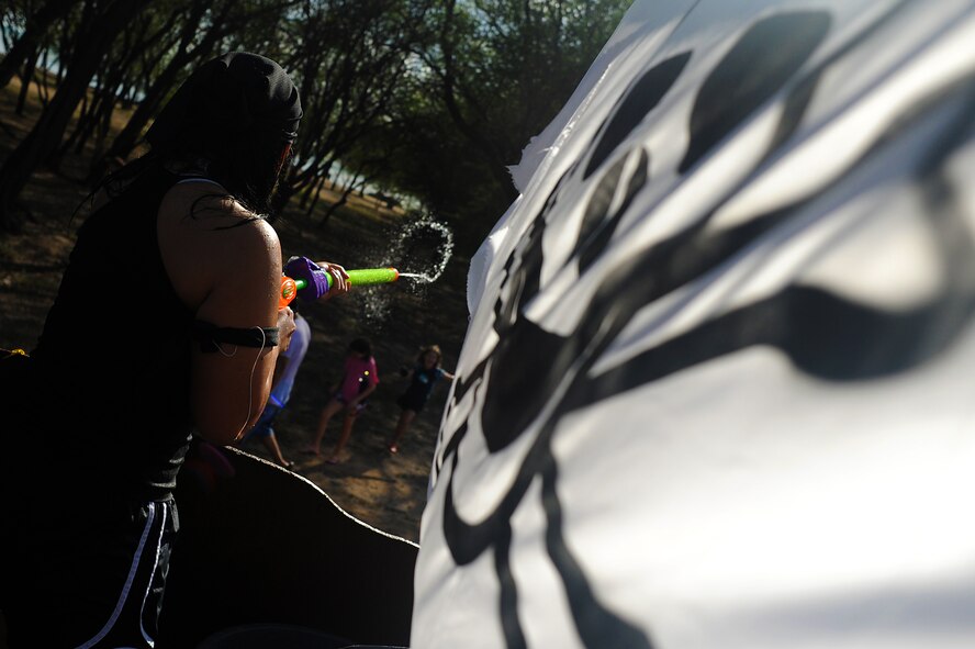 JOINT BASE PEARL HARBOR HICKAM, Hawaii -- Senior Airman Yommala Xaysanith, 15th Aircraft Maintenance Squadron, fires upon parade watchers during the annual Beach Bum Parade May 21 on Hickam. The pirate ship themed float utilized water balloons, water guns and water cannons to douse spectators as they rolled along the three-quarter mile and water hoses as they rolled by in the parade. The parade began at Bishop's Point Pier and ended at Hickam Harbor with free food and entertainment at Foster Point Pavilion. Those who wanted to were able to campout at Hickam Harbor after the parade for a fun, family night, gathered around a campfire for free s'mores. Once the sun set, campers enjoyed a movie on the beach on a large outdoor movie screen. The 15th Maintenance Group took first prize for the second year in a row for the best float. (U.S. Air Force photo/Staff Sgt. Mike Meares)