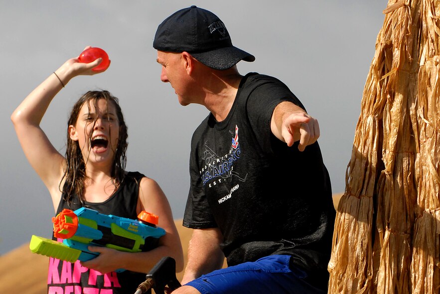 JOINT BASE PEARL HARBOR HICKAM, Hawaii -- Col. Sam Barrett, 15th Wing commander, leads the charge with his daughter Sydney, during the annual Beach Bum Parade May 21 on Hickam. Colonel Barrett and his family took on spectators with water balloons, fire hoses, water guns, water cannons and water hoses as they rolled by in the parade. The parade began at Bishop?s Point Pier and ended at Hickam Harbor with free food and entertainment at Foster Point Pavilion. Those who wanted to were able to campout at Hickam Harbor after the parade for a fun, family night, gathered around a campfire for free s?mores. Once the sun set, campers enjoyed a movie on the beach on a large outdoor movie screen. (U.S. Air Force photo/Staff Sgt. Mike Meares)