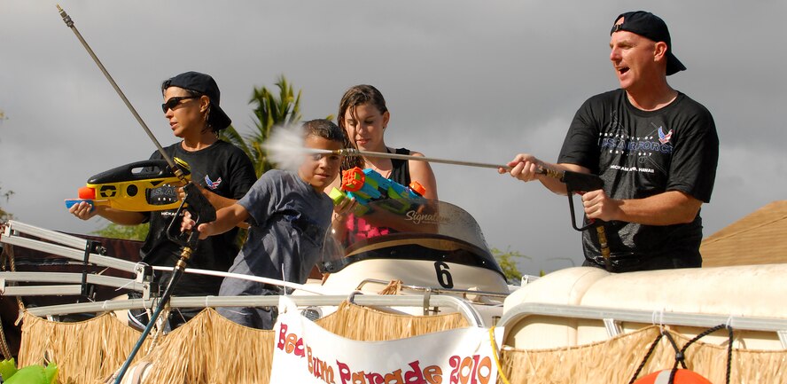 JOINT BASE PEARL HARBOR HICKAM, Hawaii -- Col. Sam Barrett, 15th Wing commander, his wife Kelly, daughter Sydney and son Sam fight against spectators with water balloons, fire hoses, water guns, water cannons and water hoses as they rolled by during the annual Beach Bum Parade May 21 on Hickam.The parade began at Bishop's Point Pier and ended at Hickam Harbor with free food and entertainment at Foster Point Pavilion. Those who wanted to were able to campout at Hickam Harbor after the parade for a fun, family night, gathered around a campfire for free s'mores. Once the sun set, campers enjoyed a movie on the beach on a large outdoor movie screen. (U.S. Air Force photo/Staff Sgt. Mike Meares)