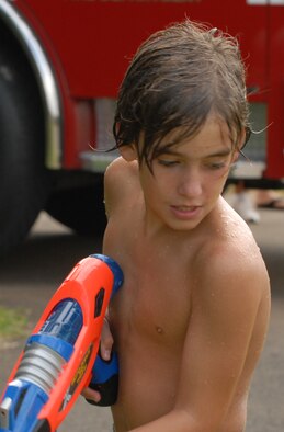 JOINT BASE PEARL HARBOR HICKAM, Hawaii -- Logan Loper water fights with spectators prior to the start of Hickam's annual Beach Bum Parade May 21. The parade began at Bishop's Point Pier and ended at Hickam Harbor with free food and entertainment at Foster Point Pavilion. Those who wanted to were able to campout at Hickam Harbor after the parade for a fun, family night, gathered around a campfire for free s'mores. Once the sun set, campers enjoyed a movie on the beach on a large outdoor movie screen. (U.S. Air Force photo/Staff Sgt. Mike Meares)