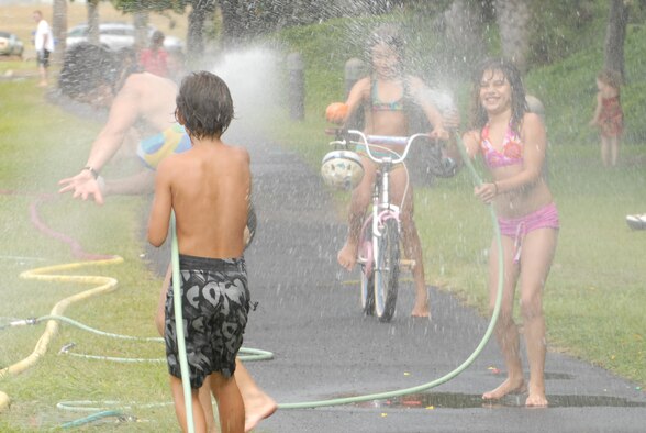 JOINT BASE PEARL HARBOR HICKAM, Hawaii -- Logan Loper water fights with spectators prior to the start of Hickam's annual Beach Bum Parade May 21. The parade began at Bishop's Point Pier and ended at Hickam Harbor with free food and entertainment at Foster Point Pavilion. Those who wanted to were able to campout at Hickam Harbor after the parade for a fun, family night, gathered around a campfire for free s'mores. Once the sun set, campers enjoyed a movie on the beach on a large outdoor movie screen. (U.S. Air Force photo/Staff Sgt. Mike Meares)