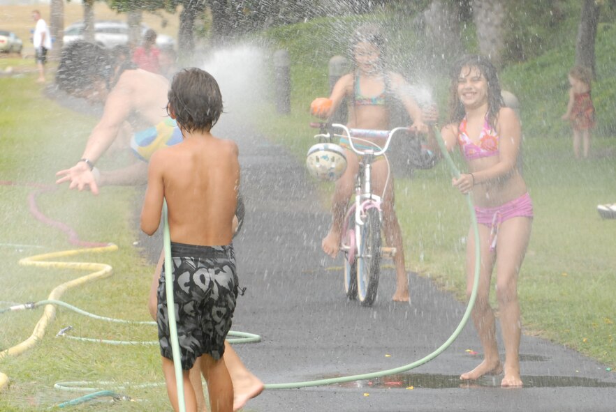 JOINT BASE PEARL HARBOR HICKAM, Hawaii -- Logan Loper water fights with spectators prior to the start of Hickam's annual Beach Bum Parade May 21. The parade began at Bishop's Point Pier and ended at Hickam Harbor with free food and entertainment at Foster Point Pavilion. Those who wanted to were able to campout at Hickam Harbor after the parade for a fun, family night, gathered around a campfire for free s'mores. Once the sun set, campers enjoyed a movie on the beach on a large outdoor movie screen. (U.S. Air Force photo/Staff Sgt. Mike Meares)