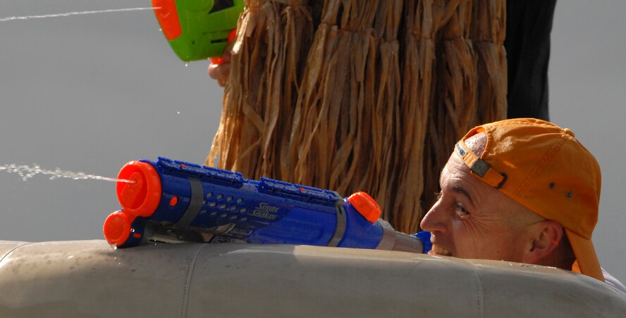 JOINT BASE PEARL HARBOR HICKAM, Hawaii -- Chief Master Sgt. Craig Recker, 15th Wing command chief master sergeant, takes cover from being attacked with a fire hose while returning fire with his water cannon during Hickam's annual Beach Bum Parade May 21. The parade began at Bishop's Point Pier and ended at Hickam Harbor with free food and entertainment at Foster Point Pavilion. Those who wanted to were able to campout at Hickam Harbor after the parade for a fun, family night, gathered around a campfire for free s'mores. Once the sun set, campers enjoyed a movie on the beach on a large outdoor movie screen. (U.S. Air Force photo/Staff Sgt. Mike Meares)