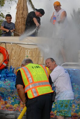 JOINT BASE PEARL HARBOR HICKAM, Hawaii -- Sam Barrett, Col. Sam Barrett, and Chief Master Sgt. Craig Recker fires their water cannons at spectators during the annual Beach Bum Parade May 21 on Hickam. Colonel Barrett, 15th Wing commander, and his family took on spectators with water balloons, fire hoses, water guns, water cannons and water hoses as they rolled by in the parade. Parade began at Bishop's Point Pier and ended at Hickam Harbor with free food and entertainment at Foster Point Pavilion. Those who wanted to were able to campout at Hickam Harbor after the parade for a fun, family night, gathered around a campfire for free s'mores. Once the sun set, campers enjoyed a movie on the beach on a large outdoor movie screen. Chief Recker is the 15th Wing's command chief master sergeant. (U.S. Air Force photo/Staff Sgt. Mike Meares)