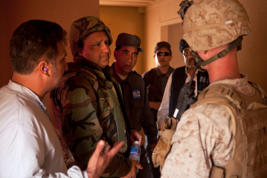 Yousef Noor, Afghan foreign language specialist, Defense Training Systems, and a native of Kabul, Afghanistan, discusses the effects of an improvised explosive device blast with 1st Lt. Derek McVay, heavy machine gun platoon commander, 1st platoon, Company W, 2nd Battalion, 3rd Marines, during a dismounted patrol at Marine Corps Training Area Bellows May 26. “The Marines handled this situation very calmly and in a professional manner,” Noor said. “They went through a lot but stayed on top of things while maintaining security in the town.”