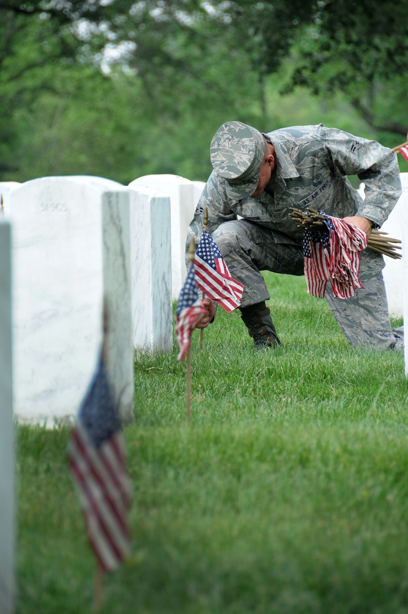 Airman 1st Class Matthew Acheson, U.S. Air Force Honor Guard ceremonial guardsman, places flags at Arlington National Cemetery headstones May 27 in honor of  America's fallen heroes. The flags-in ceremony was held in conjunction with the Memorial Day weekend.  (U.S. Air Force photo by Thomas Dennis)