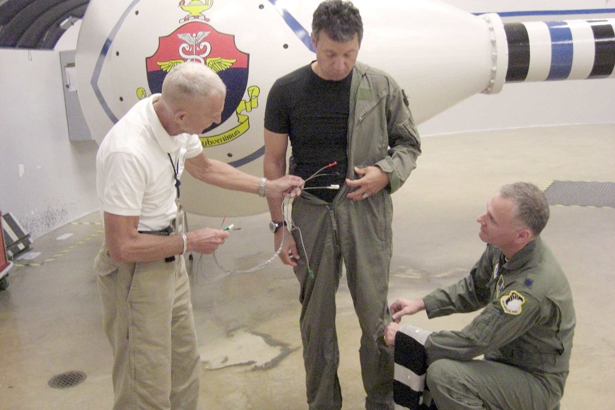 Lt. Col. Lance Annicelli (right) and Dr. Ulf Balldin (left) fit retired Capt. James Kisner with a prototype muscle stimulation suit to perform a centrifuge test as part of an acceleration protection research project they are conducting May 25, 2010, at Brooks City-Base, Texas. The three men designed a garment to be worn by pilots that will automatically sense and contract lower body muscles during and throughout excessive G-forces during flight. (U.S. Air Force photo/Durrell Bess)