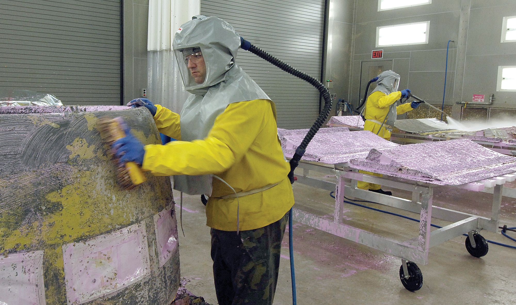 New booths to depaint, scuff preparation and paint aircraft parts are making their debut in the 551st Commodities Maintenance Squadron area of Bldg. 9001. Painters Zach Boydstun, front, scrubs loosened paint, primer and the pink paint stripper from a 
B-52 nose cowling while Tom Guardiola uses a high-powered water spray to remove the same from KC-135 spoilers. (Air Force photo by Margo Wright)