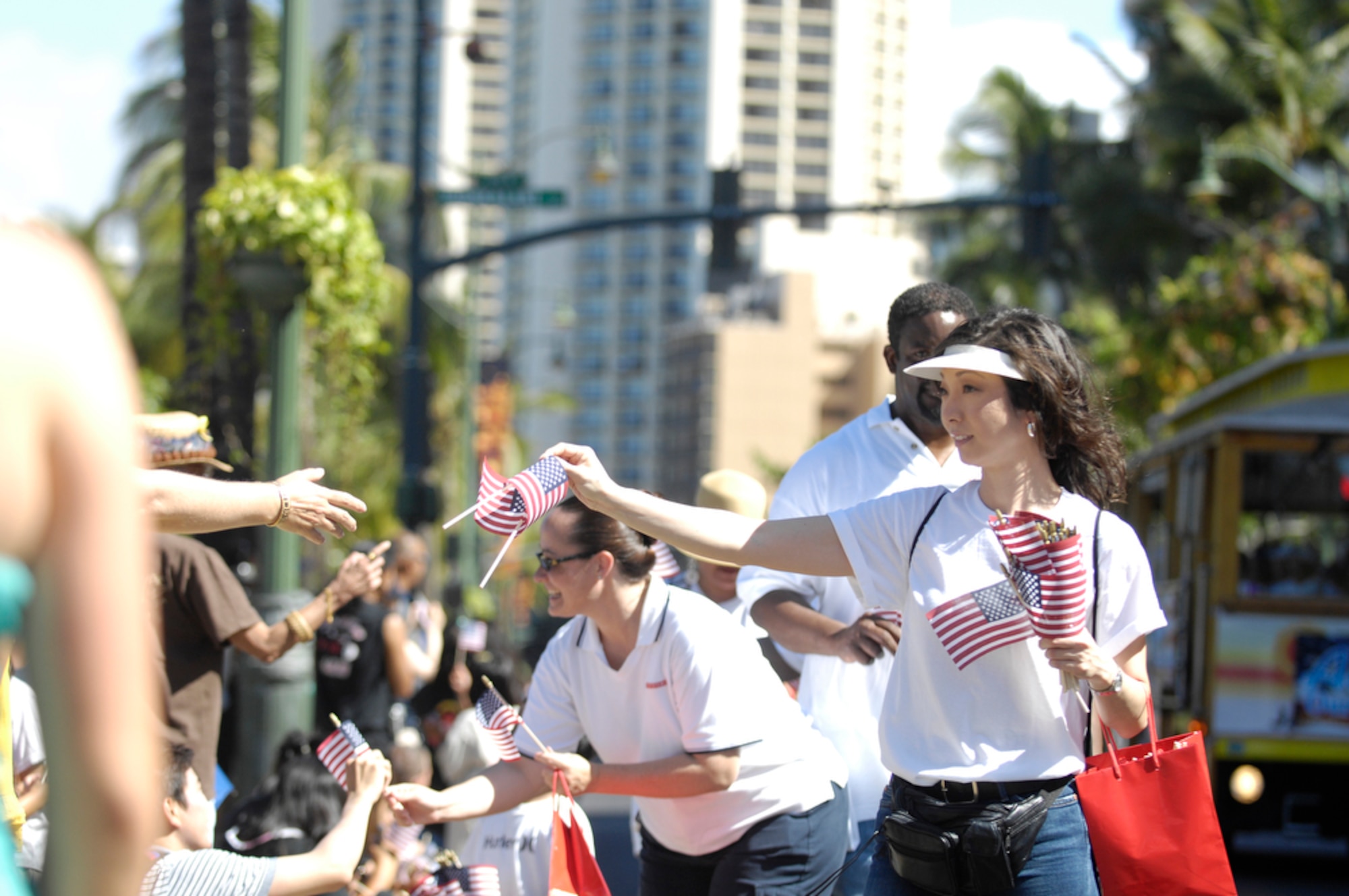 HONOLULU - An employee for BAE Systems passes out flags to onlookers of a parade as active duty, guard and reserve personnel marched in a Welcome Home Parade for the military on May 22 in Honolulu, Hawaii. The parade was followed up with entertainment at the Waikiki Shell with performances by four local Hawaii bands and a military joint jazz ensemble. The event was organized by the USO, the Chamber of Commerce Military Affairs Council and BAE Systems. (U.S.  Air Force photo/Tech Sgt. Cohen A. Young)