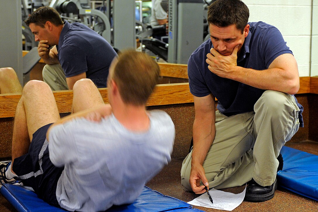 (Right) Zane McCausland, 28th Force Support Squadron fitness testing technician, admininsters the sit-up portion of a physical training test, May 26. The fitness assessment cell began administering PT tests here May 1. (U.S. Air Force photo/Airman 1st Class Matthew Flynn)