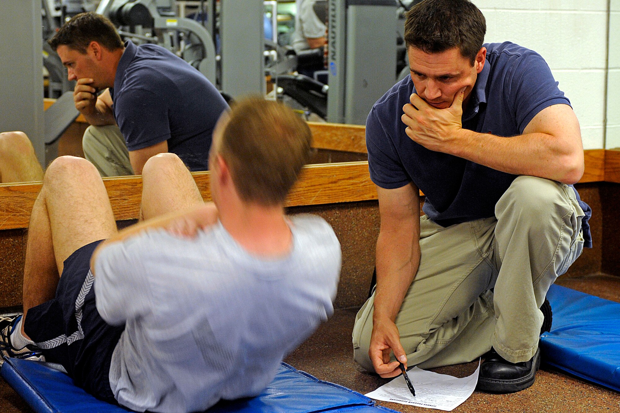 (Right) Zane McCausland, 28th Force Support Squadron fitness testing technician, admininsters the sit-up portion of a physical training test, May 26. The fitness assessment cell began administering PT tests here May 1. (U.S. Air Force photo/Airman 1st Class Matthew Flynn)