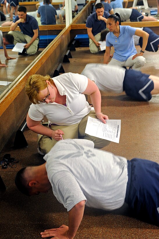 ELLSWORTH AIR FORCE BASE, S.D. – (Kneeling front to back) Karla Barker, Patty Marchitello and Zane McCausland, 28th Force Support Squadron fitness testing technicians, administer the push-up portion of a physical training test, May 26. The new PT standards will take effect on July 1. (U.S. Air Force photo/Airman 1st Class Matthew Flynn)
