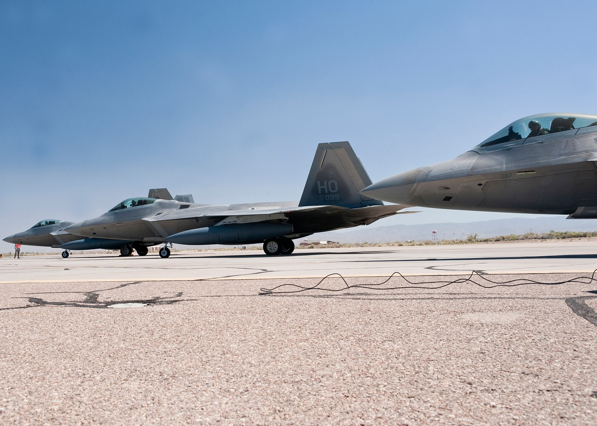 HOLLOMAN AIR FORCE BASE, N.M. -- Three F-22 Raptors prepare for takeoff at the end of the runway after receiving a final inspection May 24, 2010. F-22's from Holloman deployed to Kadena Air Base, Japan, for approximately four months as part of a U.S. Pacific Command Theater Security Package. (U.S. Air Force photo by Senior Airman DeAndre Curtiss / Released)
