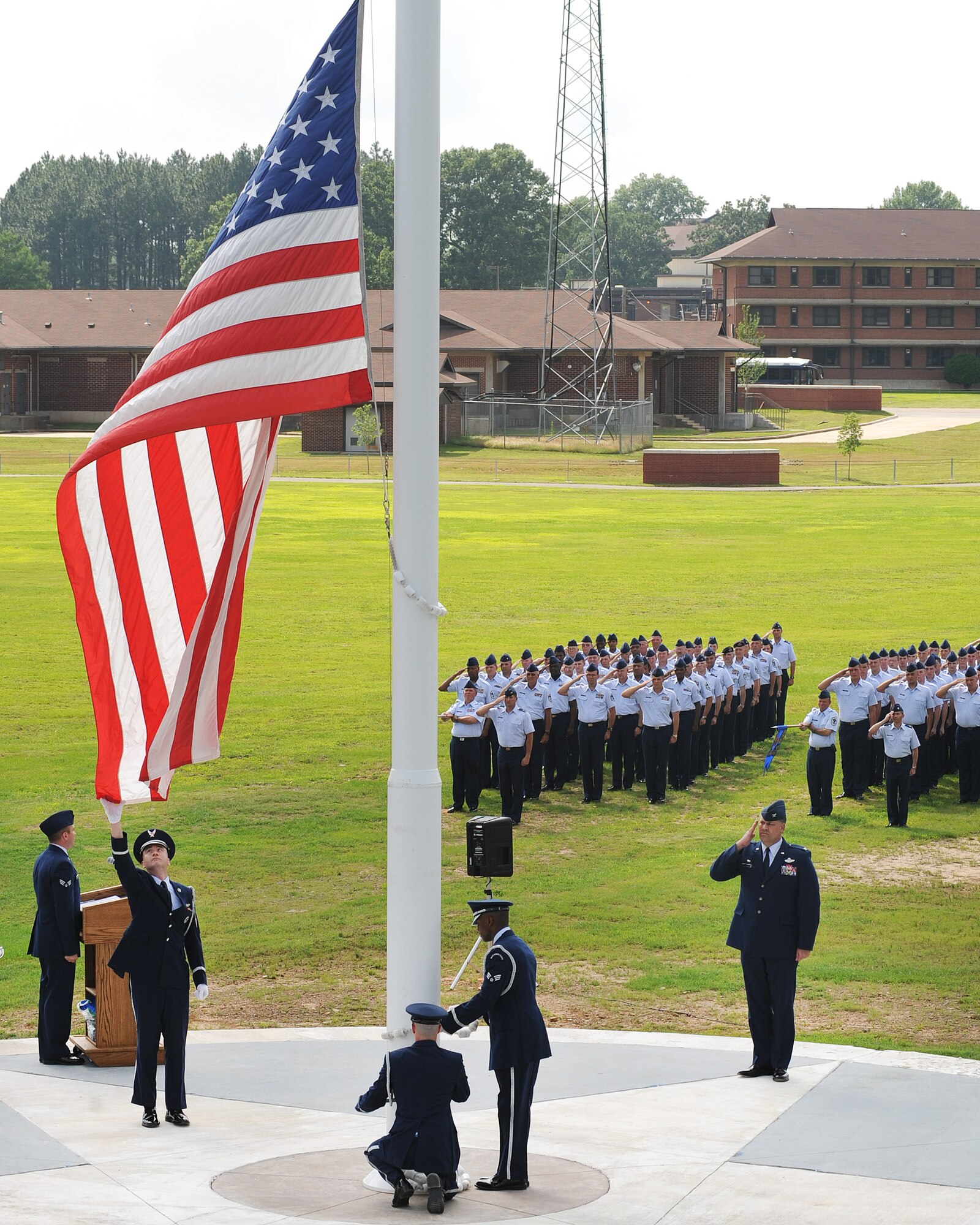 A member of the Little Rock Air Force Base Honor Guard reaches out to retrieve the stars and stripes during the base Memorial Day retreat ceremony May 26, while Col. Greg Otey, 19th Airlift Wing commander, and base personnel salute. Memorial Day commemorates the men and women of the armed forces who have given the ultimate sacrifice while in military service.  (U.S. Air Force photo by Staff Sgt. Chad Chisholm)