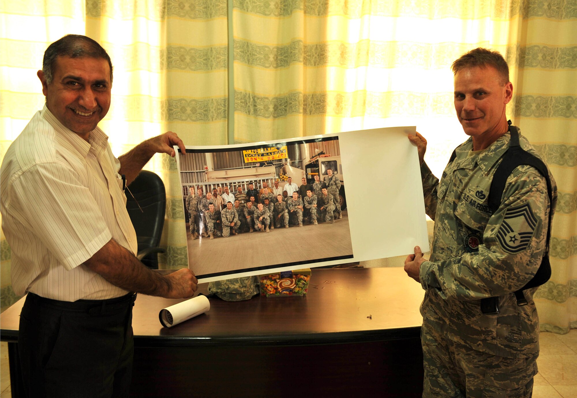 Chief Master Sgt. David Fain presents Fire Chief Basim Muhammad Salehwith a photo at Bakir Village, Iraq, May 7, 2010.  Chief Fain is the fire chief of the 332nd Expeditionary Civil Engineer Squadron, Joint Base Balad, Iraq.  (U.S. Air Force photo/Staff Sgt. Quinton Russ/released)	