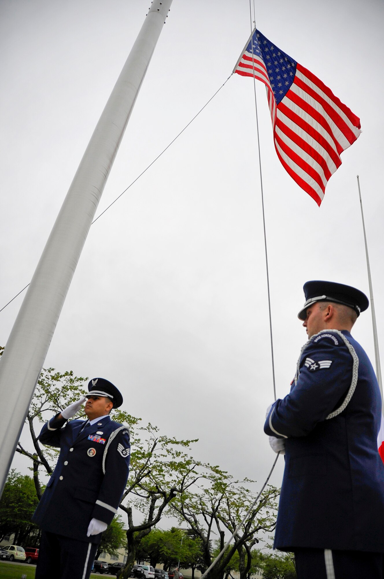 MISAWA AIR BASE, Japan -- Senior Airman Arnold Appel lowers the flag as Staff Sgt. Juan Rodriguez renders a salute during the Memorial Day retreat ceremony May 27. The base honor guard members performed in front of more than 200 people. (U.S. Air Force photo/Staff Sgt. Chad C. Strohmeyer)