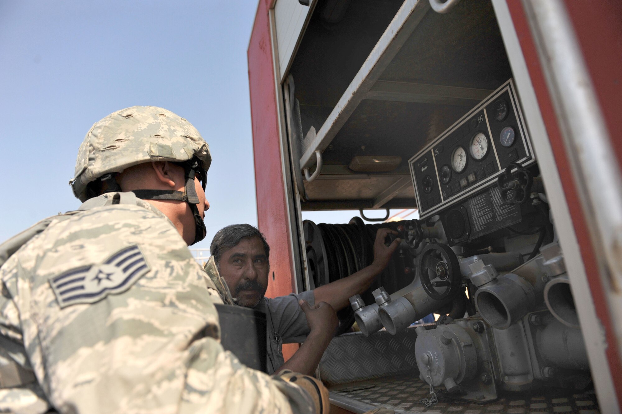 An Iraqi firefighter talks with U.S. Air Force firefighter Staff Sgt. Steven Sanabria at Bakir Village, Iraq, May 7, 2010.  Sergeant Sanabria is deployed to the 332nd Expeditionary Civil Engineer Squadron, Joint Base Balad, Iraq.  (U.S. Air Force photo/Staff Sgt. Quinton Russ/released)	