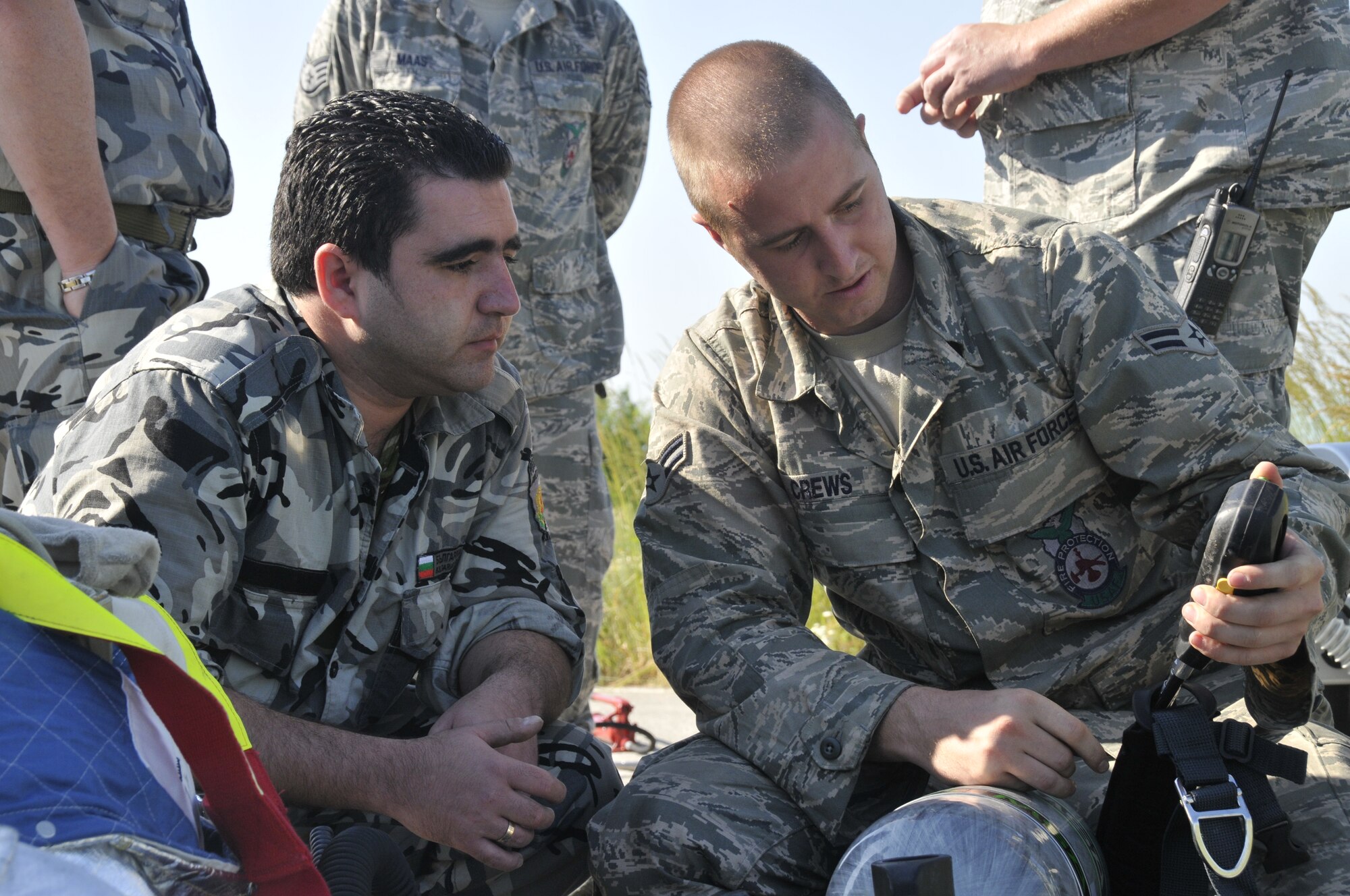 GRAF IGNATIEVO AIR FORCE BASE, Bulgaria - Airman 1st Class Phillip Crews (right), 48th Civil Engineer Squadron firefighter, explains the breathing apparatus used by American Airmen to Bulgarian air force Private Christin Atanasov, Graf Ignatievo Air Force Base firefighter. Airman Crews is in Bulgaria as part of joint-exercise Sentry Gold, an exercised designed to continue Bulgaria's integration into NATO and build partnerships between the two air forces. (Photo by Tech. Sgt. Chris Stagner)