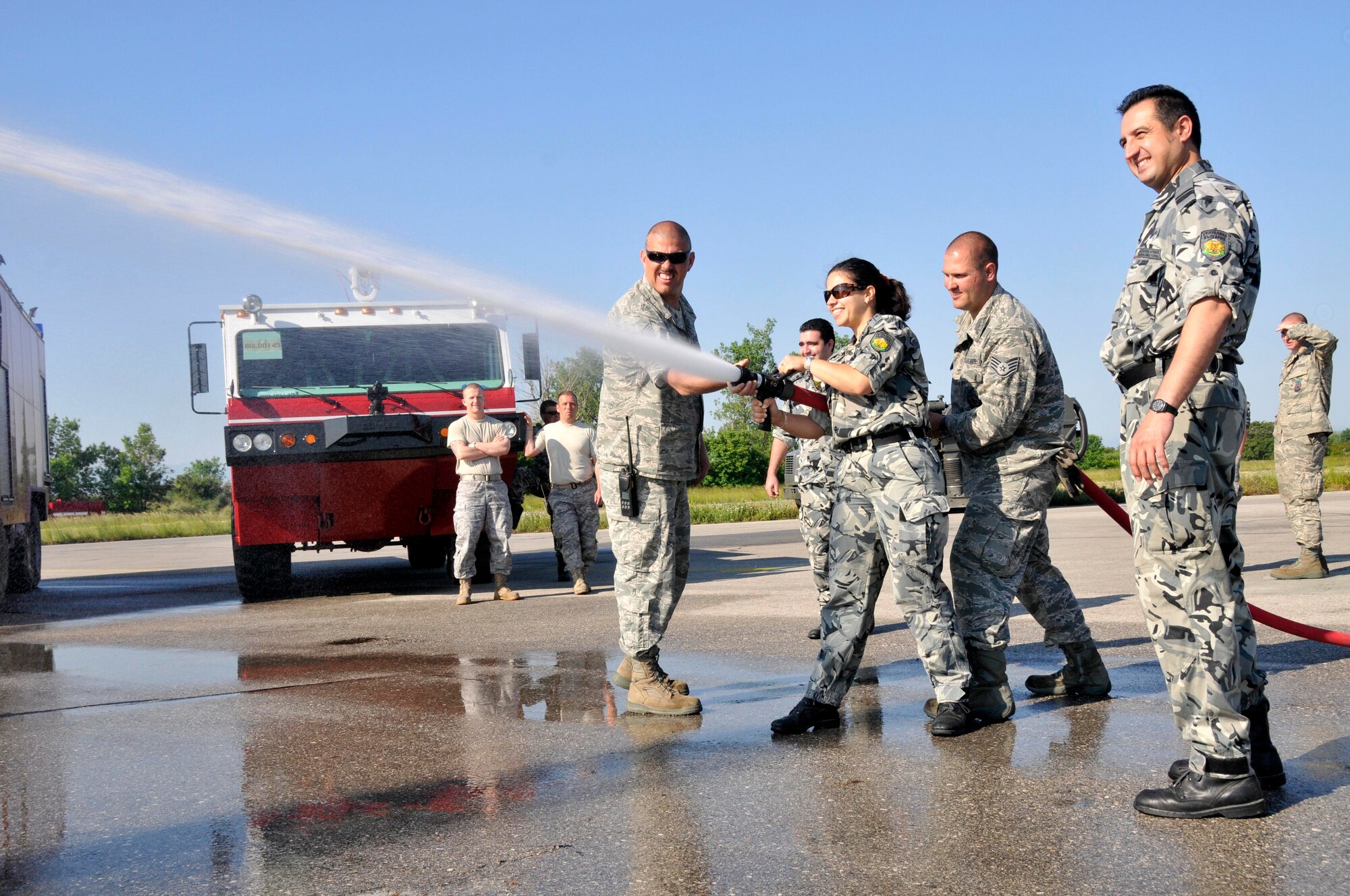 GRAF IGNATIEVO AIR FORCE BASE, Bulgaria - (Left to right) Tech. Sgt. Charles Derflinger (left), 48th Civil Engineer Squadron Fire Department station chief, and Staff Sgt. Brian Mass, 48th CES fire fighter (second from right), show Bulgarian air force Capt. Margarita Kumanova (center), Graf Ignatievo fire fighter, the differences between the two air forces water hoses. Bulgarian water hoses focus on pressure while American water hoses focus on quantity. Airmen from the Bulgarian and American air forces spent the day together building partnerships. (Photo by Tech. Sgt. Chris Stagner)