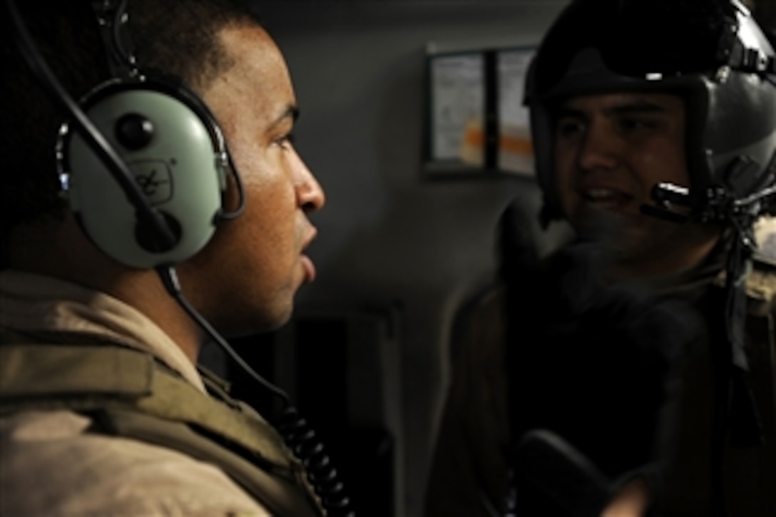 U.S. Air Force Senior Airman Kevin Johnson (left) and Senior Airman Brandon Ybarra, both C-17 Globemaster III loadmasters assigned to the 816th Expeditionary Airlift Squadron, exchange information during an airdrop mission over Afghanistan on May 9, 2010.  