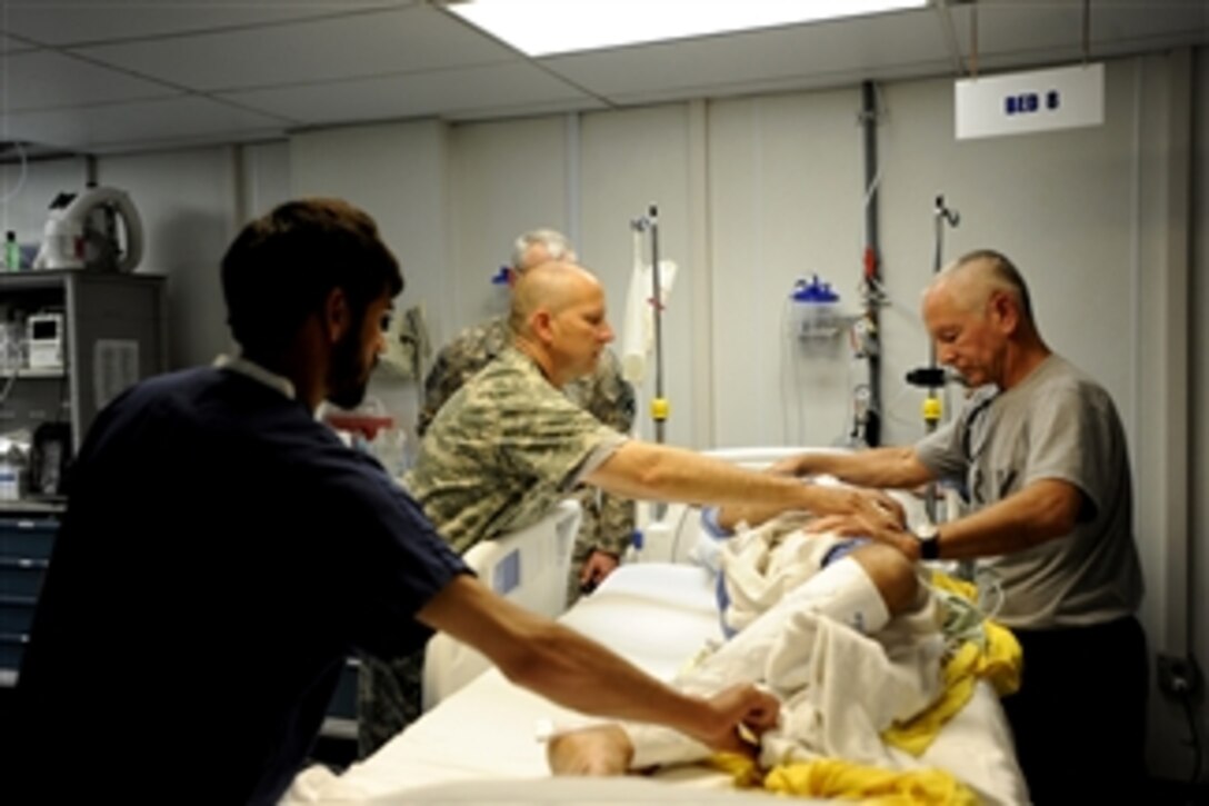 U.S. Army Capt. Andrew Kontowicz (2nd from right), a nurse assigned to the 452nd Combat Support Hospital, and Lt. Col. Davis Williams (right), an internal medicine physician assigned to the 452nd Combat Support Hospital, with the help of an Afghan nurse (left) conduct an assessment of a patient medically evacuated from the Craig Joint Theater Hospital at Bagram Airfield, Afghanistan, to Forward Operating Base Salerno, Afghanistan, on May 12, 2010.  