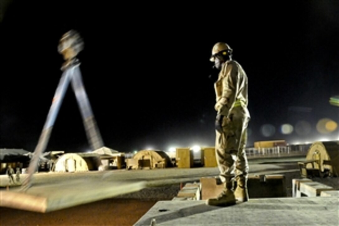 U.S. Navy Petty Officer 2nd Class Alain Gbla helps direct crane operations on Camp Leatherneck, Afghanistan, May 19, 2010. Gbla, a Seabee, is assigned to Naval Mobile Construction Battalion 5, currently deployed to Afghanistan to perform general engineering, infrastructure construction and project management.