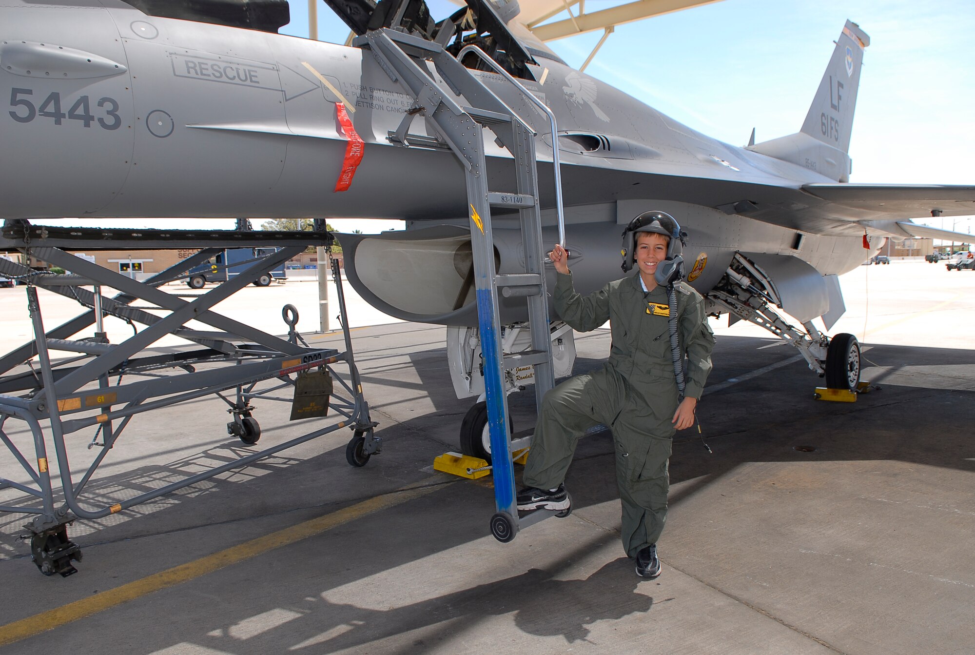 Pilot-for-a-day Alex Ramsperger, 11, stands beside an F-16 Fighting Falcon on the flightline of the 61st Fighter Squadron May 18. (Photo by Airman 1st Class Ronifel Yasay)