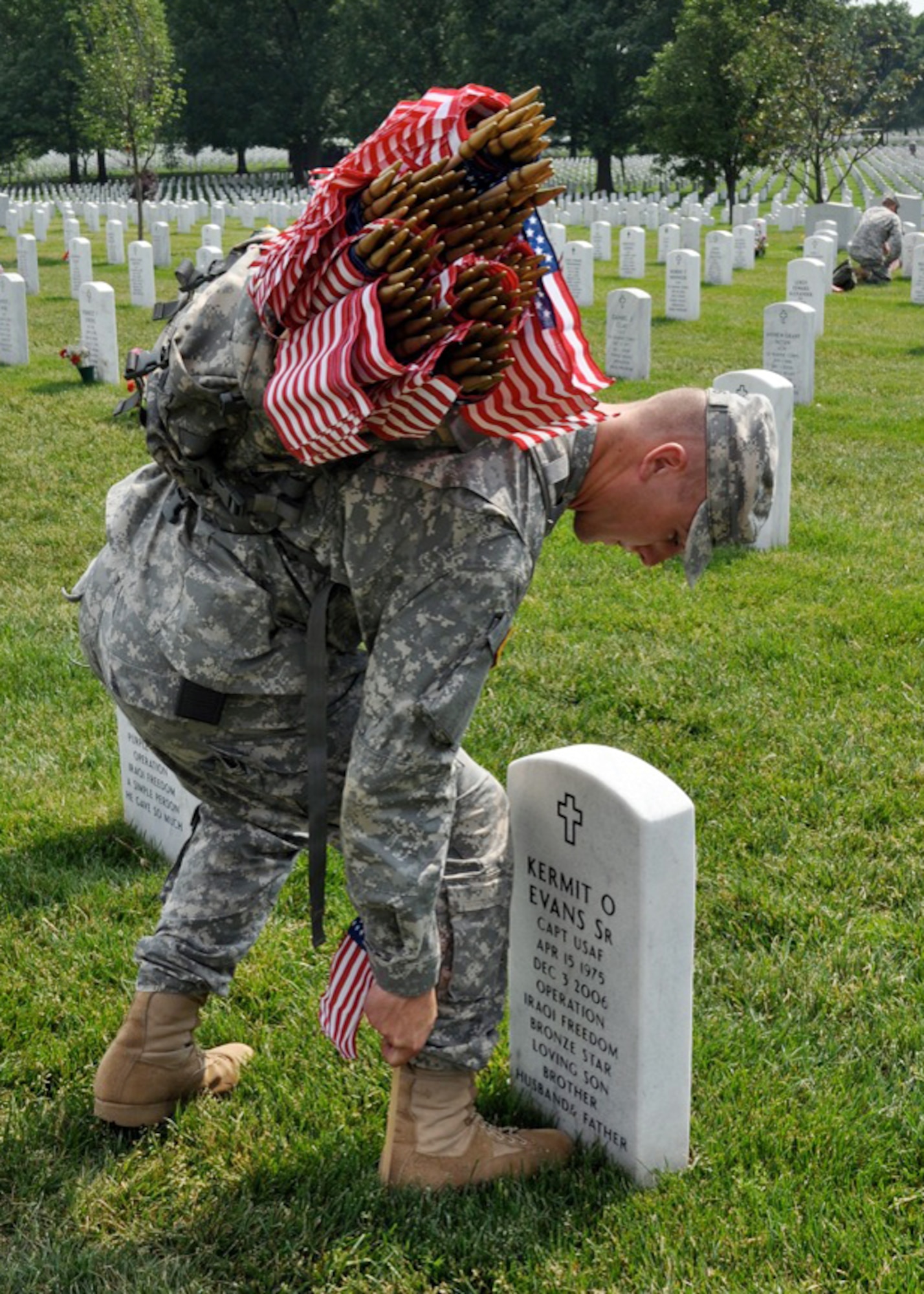 A Soldier places a flag on the grave of Capt. Kermit Evans during a Flags-In Ceremony at Arlington National Cemetery, Fort Myer, Va., May 26, in preparation for Memorial Day 2010 observances. Capt. Evans was killed Dec.3, 2006, in a helicopter crash in Iraq. He was deployed from Cannon Air Force Base, N.M., where he was the Explosive Ordnance Disposal flight commander. (Courtesy photo by Capt. Daniel J. Watson)