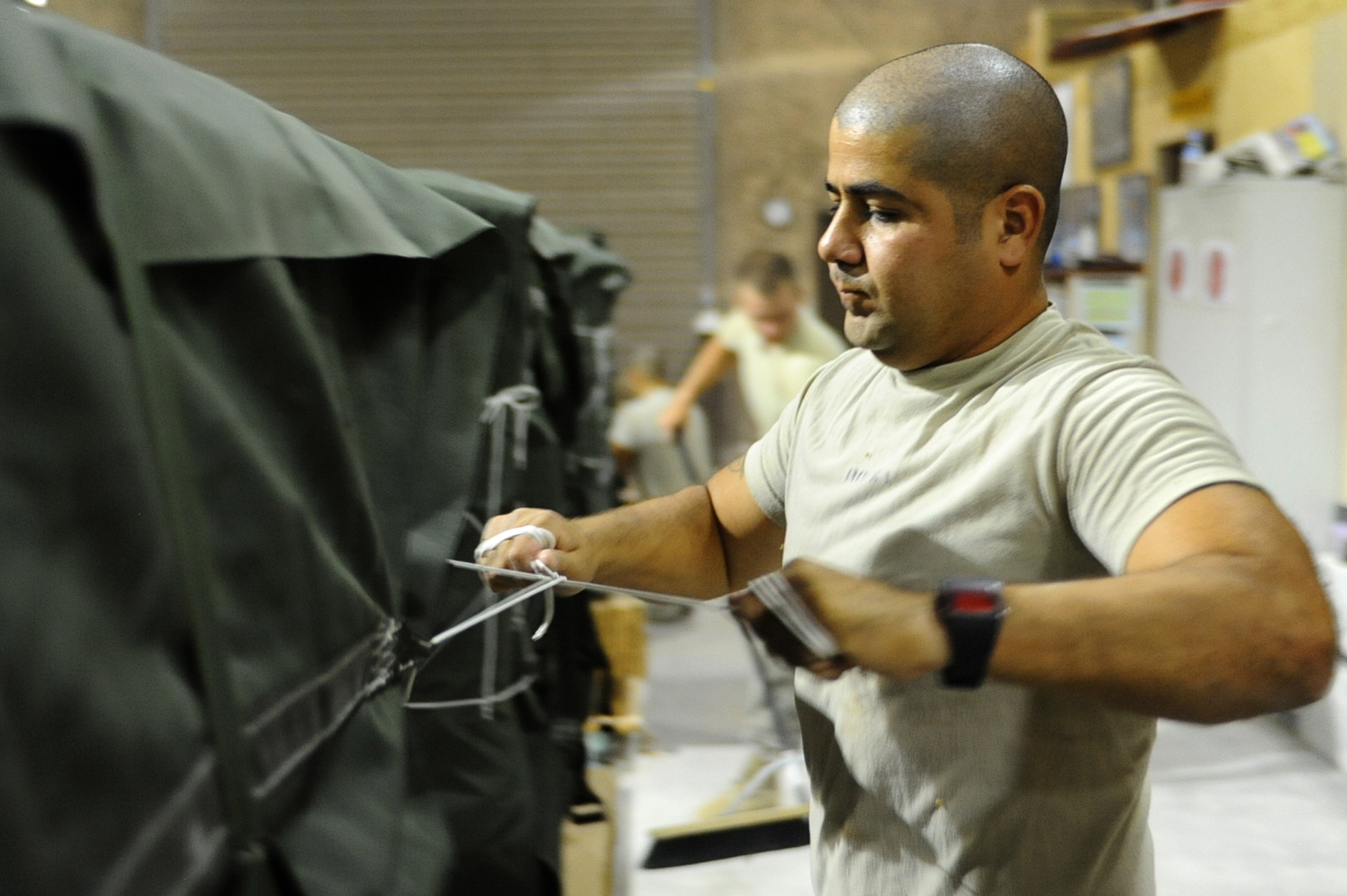 Army Spc. Carlos Rossi, 824th Quartermaster Company, Det. 9, parachute rigger, secures an A22 container on a water pallet at a non-disclosed Southwest Asia location May 19, 2010. The 824 QM CO prepares supply pallets and parachutes for air drop deliveries to Iraq and Afghanistan. (U.S. Air Force photo by Senior Airman Kasey Zickmund)[RELEASED]